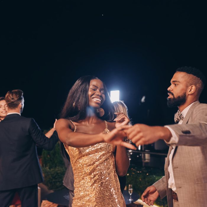 Beautiful young people dancing and smiling while spending time on luxury party